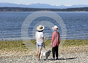 Mother, daughter and their dog looking out into Puget sound with Olympic mountains visible
