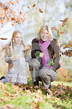 Mother and daughter throwing leaves in the air