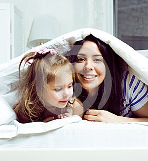 Mother with daughter together in bed smiling, happy family close