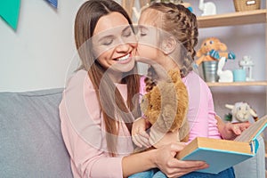 Mother and daughter together at home woman reading book to girl