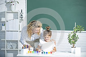 Mother and daughter together paint. Teacher helps the pupil child girl.