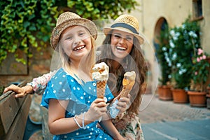 mother and daughter tourists sitting at bench and eating ice cream