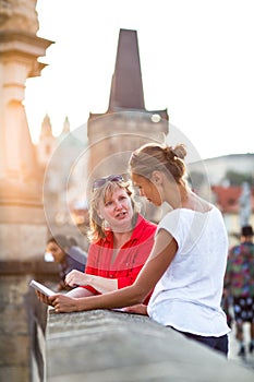 Mother and daughter traveling - two tourists studying a map