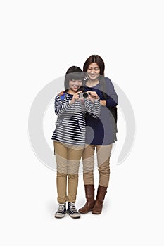 Mother and daughter trying digital camera, studio shot