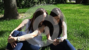 Mother and daughter use information technology of mobile phone in the park