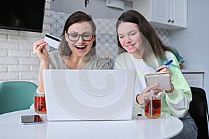 Mother and daughter using laptop credit card and doing online shopping