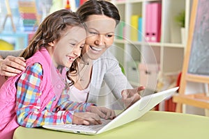 mother and daughter using laptop at home