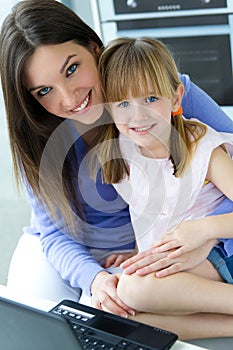 Mother and daughter using laptop in the kitchen