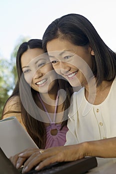Mother And Daughter Using Laptop Outdoors