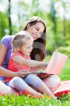 Mother and daughter using laptop outdoors