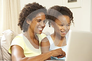 Mother And Daughter Using Laptop On Sofa At Home