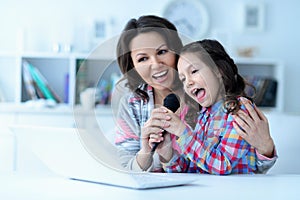 Mother and daughter using laptop together singing