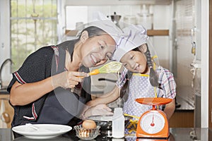 Mother and daughter using whisk to mix egg and wheat flour