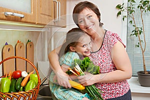 Mother and daughter with vegetables and fresh fruits in kitchen interior. Parent and child. Healthy food concept