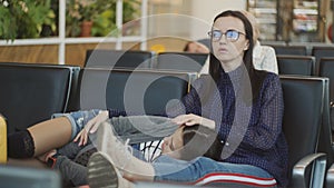 The mother and daughter in the waiting room of the airport sleeping on chairs