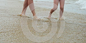 Mother and daughter walk along the seashore. family summer vacation. feet on the water. background for the design.