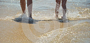 Mother and daughter walk along the seashore. family summer vacation. feet on the water. background for the design.