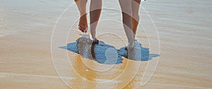Mother and daughter walk along the seashore. family summer vacation. feet on the water. background for the design.