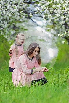 mother and daughter walk through a blooming garden