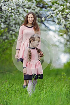 mother and daughter walk through a blooming garden