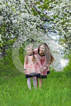 mother and daughter walk through a blooming garden