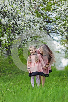 mother and daughter walk through a blooming garden