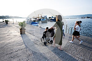 Mother and daughter walking with baby carriage on pier in the evening