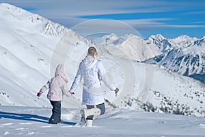 Mother and daughter walking in the mountains of the vast snow photo
