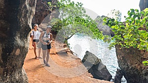 Mother and daughter walking on path next to sea