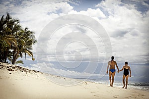 Mother and daughter walking on the pristine tropical beach