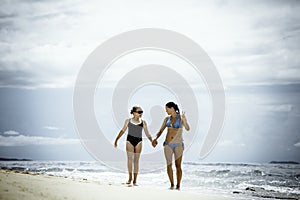 Mother and daughter walking on the pristine tropical beach