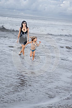 mother and daughter walking by seashore together
