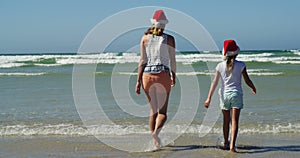 Mother and daughter walking on shore at beach on a sunny day