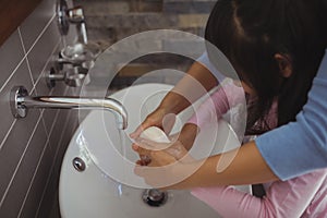 Mother and daughter washing hands in bathroom sink