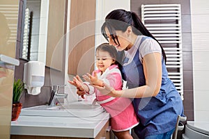 Mother and daughter washing their hands in the bathroom. Care an