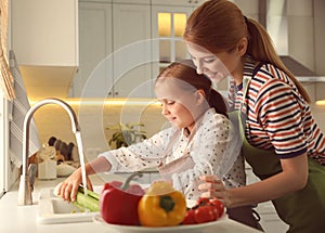 Mother and daughter washing vegetables