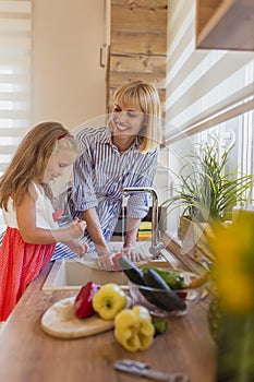 Mother and daughter washing vegetables in the kitchen sink
