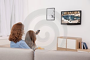 Mother and daughter watching TV on sofa