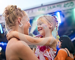 Mother With Daughter Wearing Glitter Having Fun At Outdoor Summer Music Festival 