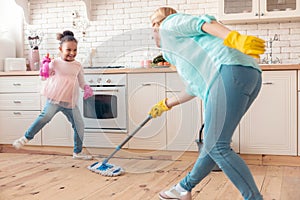 Mother and daughter wearing gloves mopping the floor in the kitchen