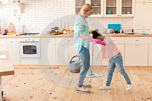 Mother and daughter wearing jeans and sneakers cleaning flat