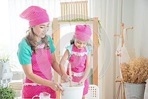 Mother and daughter wearing pink apron and hat cooking homemade bakery in kitchen room
