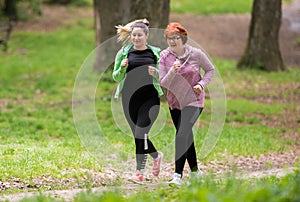 Mother and daughter wearing sportswear and running in forest at