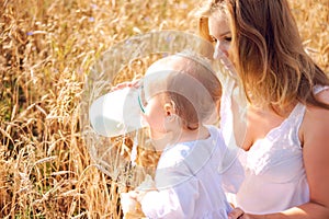 Mother and daughter in wheat field. Happy Family outdoors. healthy child with mother on picnic with bread and milk in golden