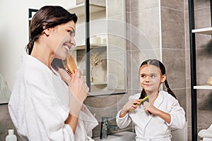 mother and daughter in white bathrobes combing