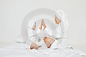 mother and daughter in white bathrobes and towels