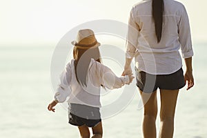 Mother and daughter who enjoy a picnic and sea bathing at the beach on sunset in holiday