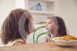 Mother With Daughter Who Is Fussy Eater Sitting Around Table At Home For Family Meal