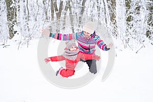 Mother and daughter on winter walk in nature. woman and child girl make snowman