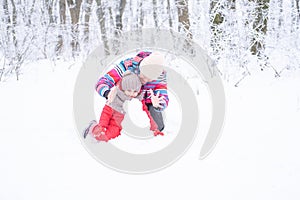 Mother and daughter on winter walk in nature. woman and child girl make snowman